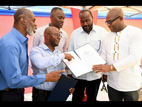 Professor Densil Williams (right), pro vice-chancellor and campus principal at The University of the West Indies (UWI), Mona looks at the contract with (from left) Professor Marvin Reid of The UWI; Milton McIntyre, of Kayani Construction Ltd; Milton Dennis