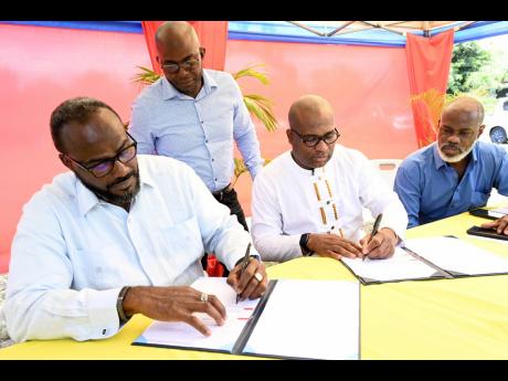 Professor Densil Williams (second right), pro vice-chancellor and campus principal at The University of the West Indies, Mona, and Christopher Bowen (left), of Wentworth Construction and Consultants Ltd, signing the contract while looking on are Milton McI