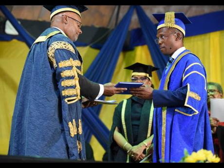 Ambassador Lloyd Carney (left), chancellor of The University of Technology Jamaica (Utech), presents the instrument of office to Dr Kevin Brown, president of UTech, during an installation ceremony at the institution’s Papine, St Andrew, main campus on Th