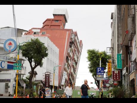 
People walk past a building, seen partially collapsed, two days after a powerful earthquake struck the city, in Hualien City, eastern Taiwan, Friday, April 5.