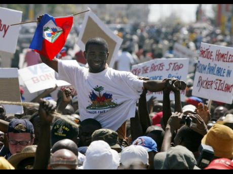 Guy Philippe, who led the rebellion against former President Jean-Bertrand Aristide, is greeted by supporters during a march of thousands in Port-au-Prince, Haiti.