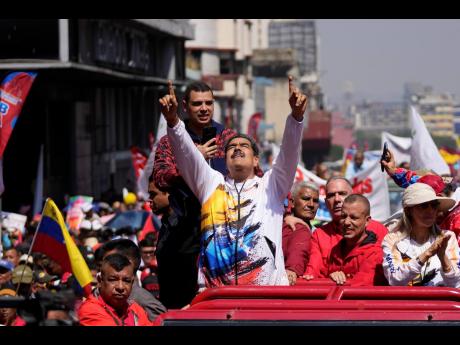Venezuelan President Nicolás Maduro points upwards as he is driven to the electoral council headquarters to register his candidacy for a third term, in Caracas. 