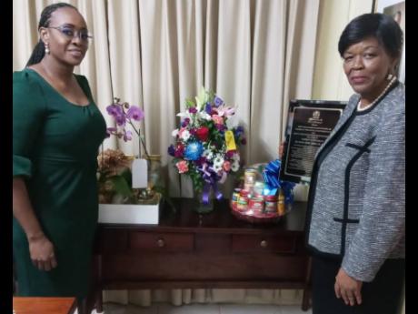 House Speaker Juliet Holness (left) poses with the retiring Clerk to the Houses of Parliament Valrie Curtis after presenting her with a citation and other goodies for her years of sterling service.