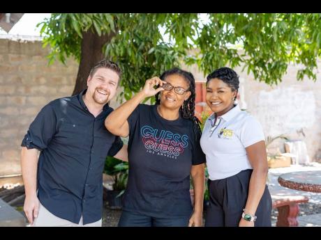 Andrea Thomas Knight (centre), one of hundreds of Jamaicans who benefitted from a free eyeglass clinic at the Fellowship Tabernacle hosted by The Best Dressed Chicken Fun In The Son and Luis Palau Association (LPA) on Tuesday April 16, gives her new glasse