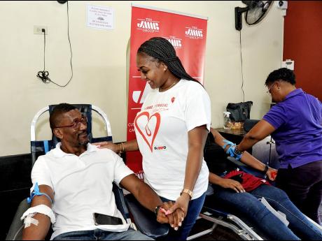 Fitzgerald Faulknor (left), IT consultant at JMMB Group, pauses during the blood donation process to have a chat with a pleased Janneal Fagan, culture & internal communication officer at JMMB Group. Also sharing in the photo op are Zedeen Dunbar (right, st
