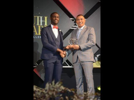 Evad Campbell (left), receives the 2023 Prime Minister National Youth Award for Excellence in music from Prime Minister Andrew Holness. 