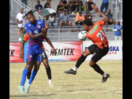 Ricardo Thomas (left) of Dunbeholden takes evasive action as Nickalia Fuller (right) of Tivoli Gardens attempts to fire a shot on goal during a recent Jamaica Premier League match at the Ashenheim Stadium, Jamaica College.