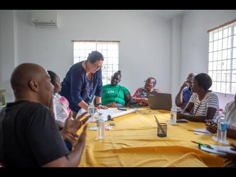 Saffrey Brown (standing), project director of Project STAR, in consultation with residents at a  working sessions facilitated by Project STAR at the Source Centre on Barracks Road in Savanna-la-Mar, Westmoreland, recently.