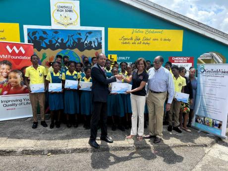 The VM Foundation recently partnered with GeoTechVision to donate 12 tablets to the Lewisville High School in St Elizabeth. Samantha Charles (centre), CEO, VM Foundation, presents one of the tablets to Duken Williams (left), principal, while Stephen Wedder