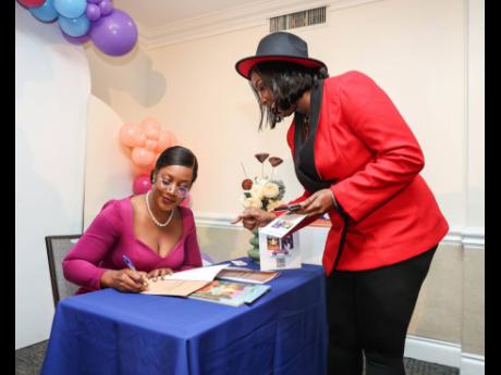 Shauna-Kaye East Bevan (right), vice president, marketing and public relations at the Jamaica Institution of Engineers, gets her signed copy of Dianne Plummer’s new children’s STEM education books, ‘A Girl’s Guide to STEM’ and ‘Science in the S