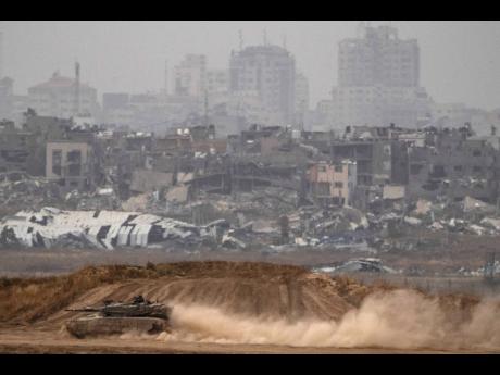 Israeli soldiers move on the top of a tank near the Israeli-Gaza border, as seen from southern Israel.