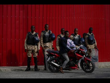 Police stand guard outside the Prime Minister’s office in Port-au-Prince, Haiti yesterday.