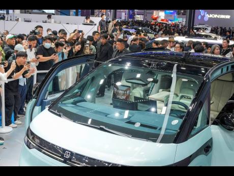 Visitors take photos of a Zeekr car during the opening of China Auto Show in Beijing, China, Thursday, April 25, 2024.