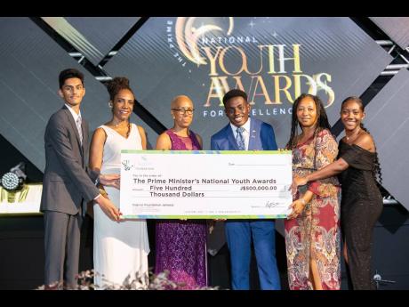 Jacqueline Donaldson (second left), vice-president, corporate services, Sagicor Group Jamaica, hands over a symbolic cheque for $500,000 to the 2024 Prime Minister Youth awardees for academic excellence, alongside Minister of Education and Youth Fayval Wil