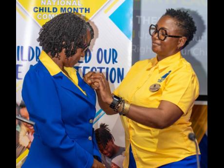 Nicole Patrick Shaw (right), newly installed chairman of the National Child Month Committee, pins Dr Pauline Mullings with the title ‘chairman emeritus’ on Thursday.