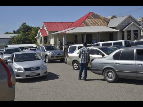 
In this October 2017 photo, a man walks by vehicles awaiting inspection at the Motor Vehicle Examination Depot, Swallowfield Road, Kingston.