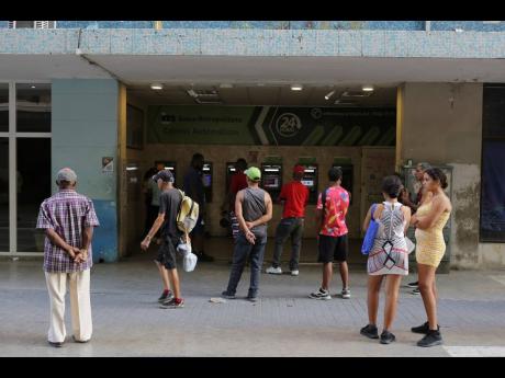 People stand in line outside a bank hoping to withdraw Cuban pesos from an ATM in Havana, Cuba, last week. An increasing number of Cubans are having to grapple with the country's shortage of cash. 
