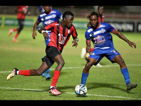 
Arnett Gardens’ Kaheim Dixon attempts to dribble by Portmore United’s Akeem Mullings during the first leg of their Jamaica Premier League play-off game at Sabina Park last Monday.