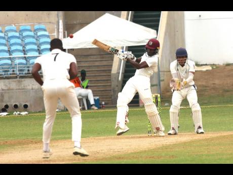
Kingston CC batsman Kirk McKenzie (centre) plays a pull shot to bring up his half-century against the Jamaica Defence Force on the opening day of the JCA Senior Cup final at Sabina Park yesterday. Looking on are bowler Kevin Daley (left) and wicketkeeper 