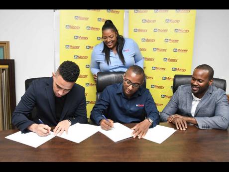 Rushio Billings, CEO and co-founder of GiftMe, and Horace Hines, general manager of JN Money Services Limited, sign the contract for the new JN Money-GiftMe partnership, while Rashidi Thomas (right), COO and co-founder of GiftMe, and Sanya Wallace, assista