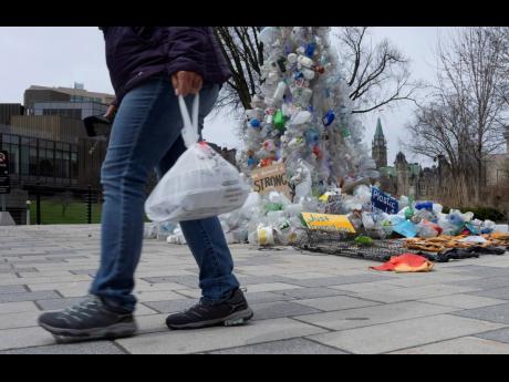 A person carries food in a plastic bag past an art installation outside the a United Nations conference on plastics on April 23, 2024, in Ottawa, Ontario.