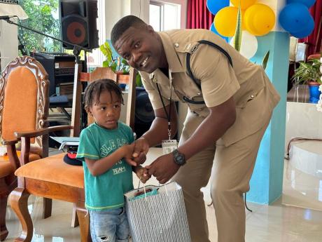 Inspector Ricardo Beckford of the Brown’s Town police, hands a bag to a student during a recent awards ceremony in Alexandria.