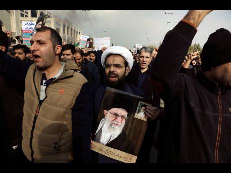 A cleric holds a poster of late Iranian Supreme Leader and  revolutionary founder Ayatollah Khomeini while chanting slogans in a demonstration over the US airstrike in Iraq that killed Iranian Revolutionary Guard Gen Qassem Soleimani in Tehran, Iran, on Ja