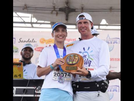 Danielle Terrier, the female winner of the 10K Run of the Jill Stewart MoBay City Run, collects her plaque from Adam Stewart, executive chairman of Sandals Resorts International.