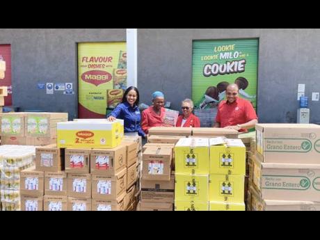 From left: Nestle’s PR Manager Camille Campbell examines the first disbursement of products under the MOU with the Jamaica Red Cross’s Director General Yvonne Clarke, President Allasandra Chung and Deputy Director Kevin Douglas. The donation incuded  a