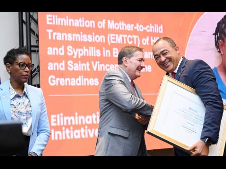 Dr Christopher Tufton (right), minister of Health and Wellness, exchanges a word while receiving a certificate from Dr Jarbas Barbosa da Silva, director of the Pan American Health Organization (PAHO), while Rhonda Sealey-Thomas, assistant director of PAHO/