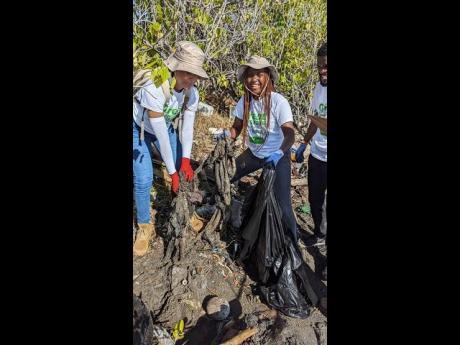 From left: Forestry Department staff member Nasheji-Gaye Elliot, public relations and communications officer, and Taniek Williams, forest technician, Biophysical Inventory Unit, demonstrate great teamwork as they remove densely entangled bags dug from the 