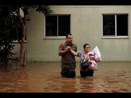 A soldier helps a woman evacuate from a neighbourhood flooded by heavy rains, in Canoas, Rio Grande do Sul state, Brazil, on Saturday.