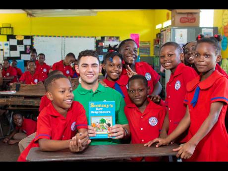 Rally driver Fraser McConnell (second left) is surrounded by children from the Waterford Primary School at the end of his Read Across Jamaica Day presentation there yesterday.  