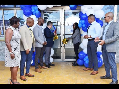 Minister without portfolio in the Ministry of Economic Growth and Job Creation Matthew Samuda (fourth left) and member of parliament for the Trelawny Northern constituency Tova Hamilton (third right) cut the ribbon during the grand opening of the National 
