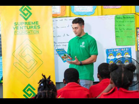 Fraser McConnell, professional Jamaican rally driver and JustBet ambassador, reads to an excited and engaged Grade 3 class at Waterford Primary School in celebration of Read Across Jamaica Day.