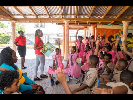 Students of the Foundation Preparatory School eagerly raise their hands to claim prizes from Pizza Hut during the quick-service restaurant’s Read Across Jamaica Day Clarendon tour. 