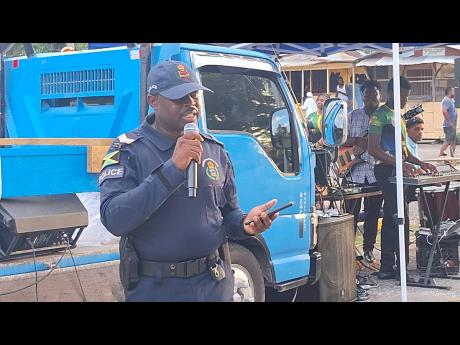 Sergeant Kenroy Easy, subofficer at the Morgan Bridge Police Station in Zone Two of the Westmoreland Police Division, addressing stakeholders in Grange Hill on Saturday night during a peace march against gang violence.