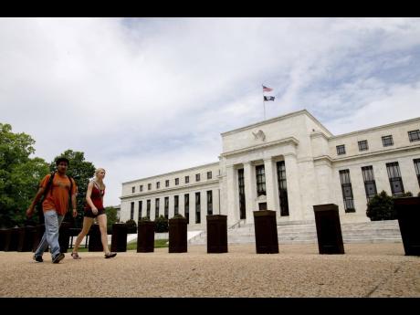 Persons walk by the US Federal Reserve building in Washington DC.