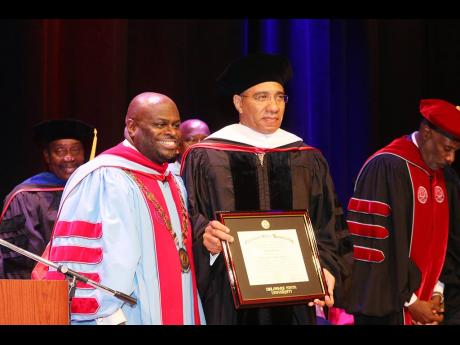 Prime Minister Andrew  Holness displays his honorary degree of Doctor of Humane Letters following the presentation by the president of Delaware State University, Dr Tony Allen, at Delaware State University. 