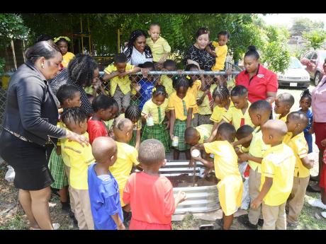Jebb Memorial Basic School students and staff members gather eagerly outdoors to prepare their newly installed raised garden plot, generously donated by Salada Foods and the ESIROM Foundation, recently. 