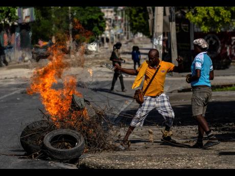 People set fire to an abandoned body, covered with branches and tires, in the Champ de Mars area of Port-au-Prince, Haiti, on Saturday, May 11, 2024. More than 2,500 people have been killed or injured from January to March, according to the United Nations,