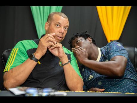 Reggae Girlz assistant coach Xavier Gilbert (right) shares a word with his head coach, Hubert Busby Jr, during a Jamaica Football Federation press conference at its headquarters in St Andrew yesterday.