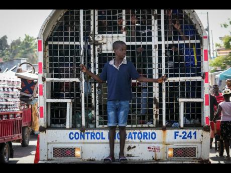 
A boy stands on the bumper step of a paddy wagon holding undocumented Haitians detained by immigration officials in Dajabon, Dominican Republic, Friday, May 17, 2024.