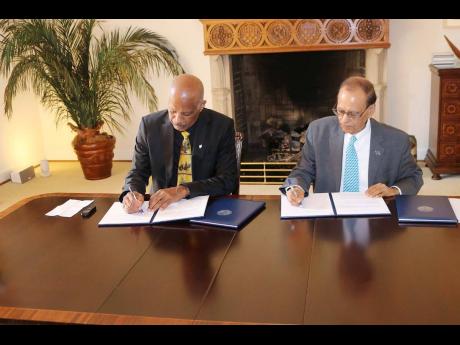 UWI Vice-Chancellor Professor Sir Hilary Beckles (left) and SUNY’s University at Buffalo President Satish K. Tripathi sign a memorandum of understanding between the two universities on May 20 to help achieve the United Nations 2030  Sustainable Developme