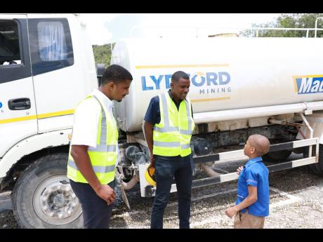 Dwight Simms (left), employee relations manager, and Jase Millington (centre), operations manager at Lydford Mining, share insights with a Camperdown student on operating the Lydford Water Truck, fostering aspirations and community engagement.