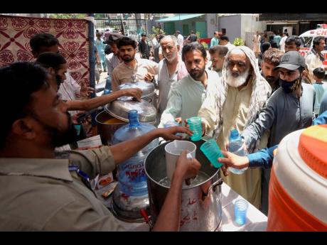 Volunteers provide lime sugar water to people at a camp set up to prevent heatstroke on a hot summer day, in Karachi, Pakistan, Thursday, May 23.
