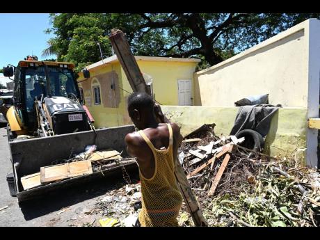 Residents clean up a section of Rose Garden in Kingston on Thursday as they, in collaboration with Carreras Limited, renovated the Rose Garden Community Centre. The Labour Day project was supported by Project STAR.
