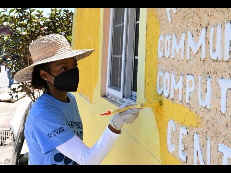 Kimberly Duffus paints a section of the Rose Garden Community Centre on Thursday.