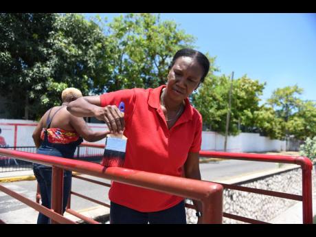 Sarah Marshall, councillor for the Trench Town division in the Kingston and St Andrew Municipal Corporation, paints a section of a footbridge in her division on Thursday.