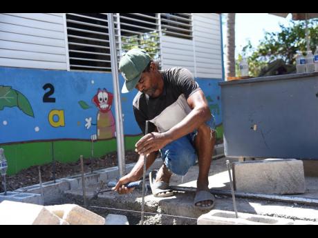 Parent Neville Stewart assists in building a classroom at the Laura’s Basic School in Duhaney Park, St Andrew, which his daughter attends.